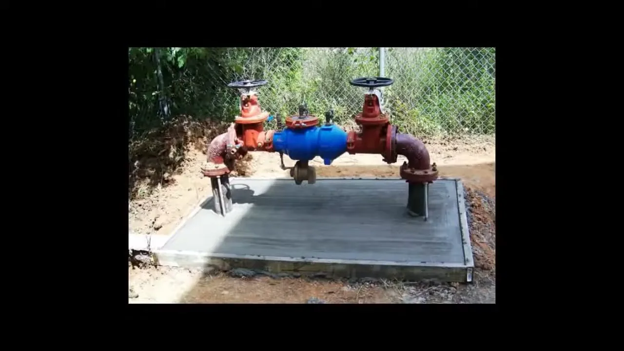Commercial fire backflow assembly on concrete pad being checked by a plumber during emergency plumbing