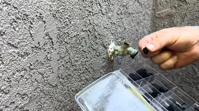 Close-up of removing hose bib screw with driver inspected as part of emergency plumbing